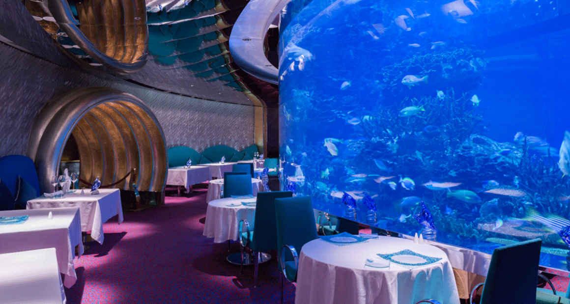 Nearly 4,000 fish species swim inside a floor-to-ceiling aquarium at the Al Mahara restaurant. Photograph by Walter Shintani