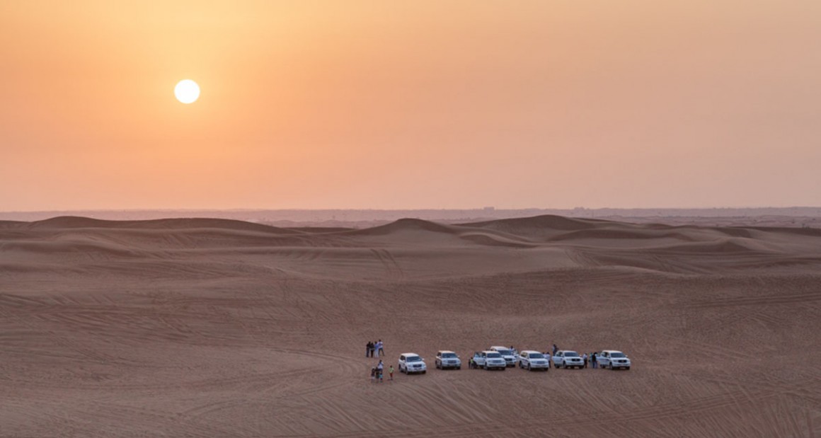 A caravan of Land Cruisers crosses the dunes. Photograph by Walter Shintani.